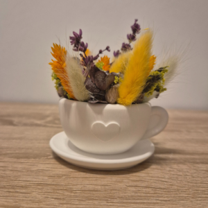 Tasse aus Gips mit Trockenblumen gefüllt auf einer Untertasse