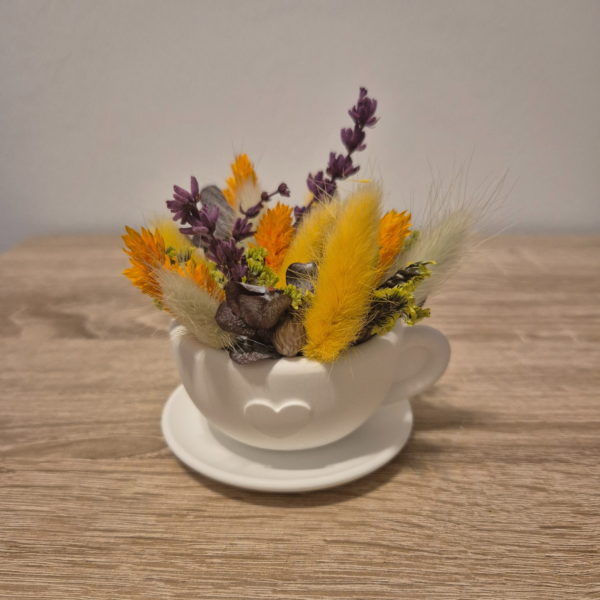 Tasse aus Gips mit Untertasse und Trockenblumen von oben