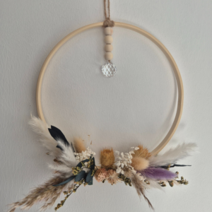 Ring aus Holz, der unterhalb mit Blumen bedeckt ist und an einem Band ist ein Diamant artiger Stein befestigt, der das Licht einfangen und in den Raum reflektieren soll