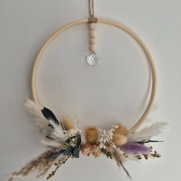 Ring aus Holz, der unterhalb mit Blumen bedeckt ist und an einem Band ist ein Diamant artiger Stein befestigt, der das Licht einfangen und in den Raum reflektieren soll