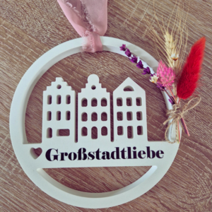 Gips Loop an einem Band zur Aufhängung befestigt. Dazu ist ein kleiner Blumenstrauß an der Seite gebunden und in der Mitte ist eine Aufschrift mit Großstadtliebe.