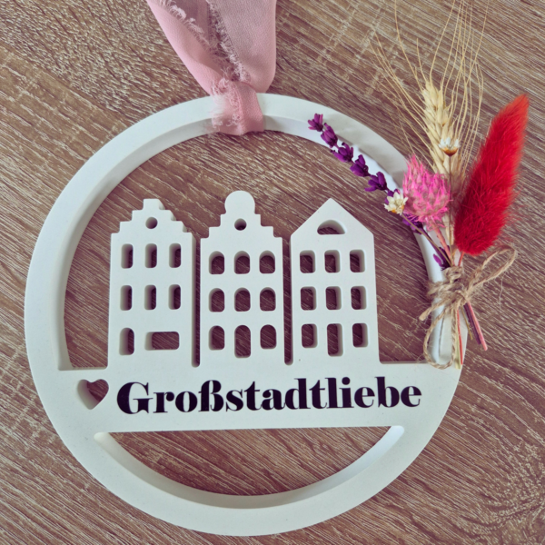 Gips Loop an einem Band zur Aufhängung befestigt. Dazu ist ein kleiner Blumenstrauß an der Seite gebunden und in der Mitte ist eine Aufschrift mit Großstadtliebe.