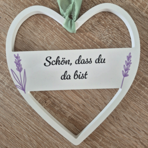 Herz aus Gips mit einem Balken in der Mitte, aus dem die Aufschrift "Schön, dass du da bist" zu sehen ist.