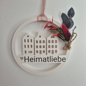 Loop aus Gips mit Häusern in der Mitte und dem Wort Heimatliebe, abgerundet von einem kleinen Strauß Trockenblumen